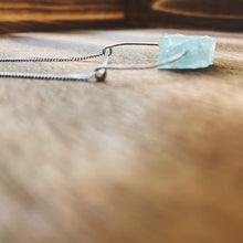 Load image into Gallery viewer, This beautiful cluster of natural rough Aquamarine stones are set on a sterling silver half-circle, hung from a dainty sterling silver curb chain, and finished with a vintage-inspired pearl box clasp.
