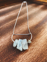 Load image into Gallery viewer, This beautiful cluster of natural rough Aquamarine stones are set on a sterling silver half-circle, hung from a dainty sterling silver curb chain, and finished with a vintage-inspired pearl box clasp.
