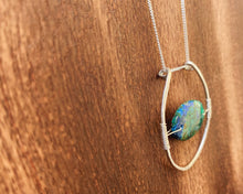 Load image into Gallery viewer, This stunning natural, mined Azurite-Malachite-Chrysocolla Pendant is 9.25 carats and has been polished into an oval cabochon and suspended upon sterling silver wire amid a sterling silver horseshoe shaped ring pendant, which hangs upon a smooth, dainty sterling silver curb chain.
