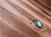 Load image into Gallery viewer, This stunning natural, mined Azurite-Malachite-Chrysocolla Pendant is 9.25 carats and has been polished into an oval cabochon and suspended upon sterling silver wire amid a sterling silver horseshoe shaped ring pendant, which hangs upon a smooth, dainty sterling silver curb chain.
