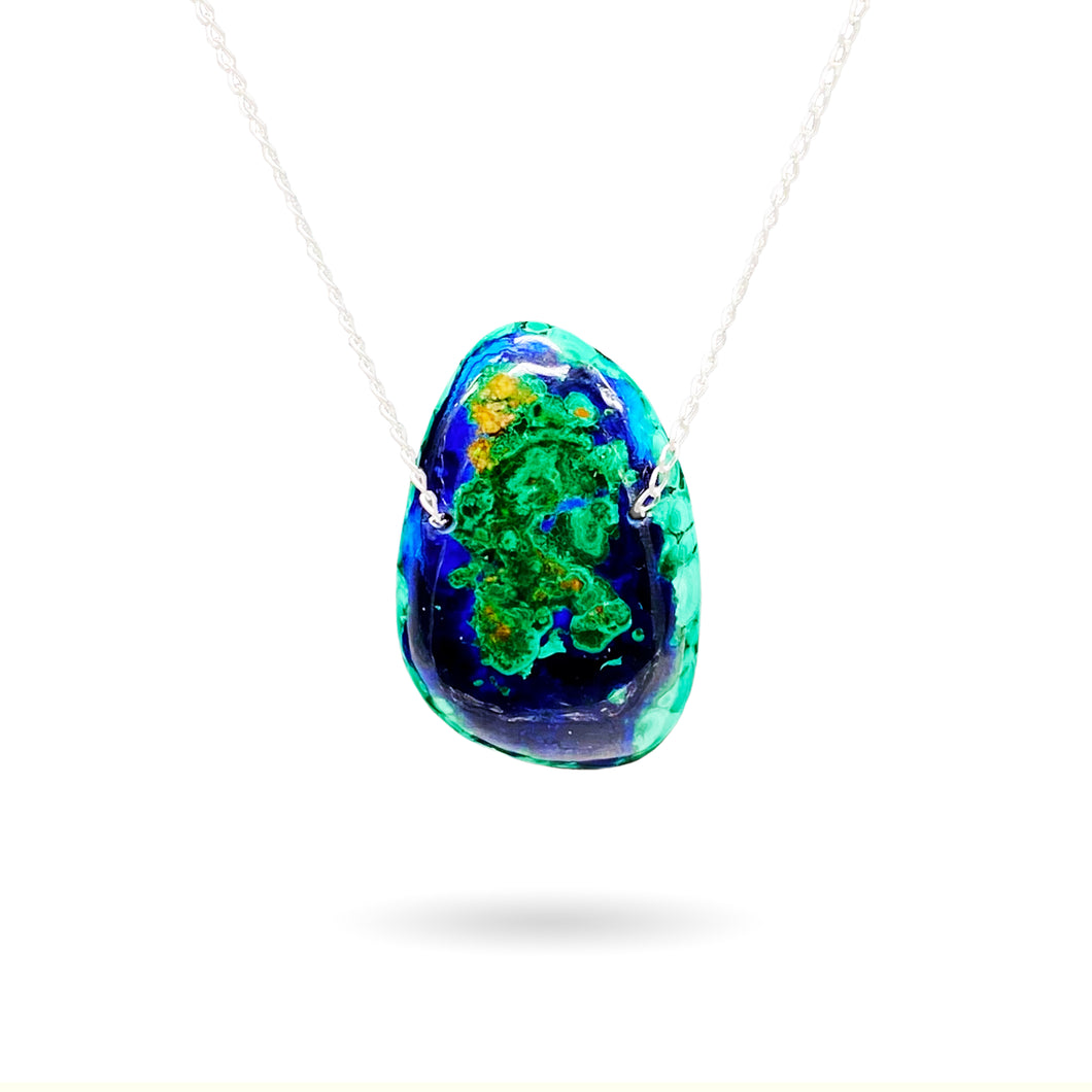 This stunning natural 85-carat Azurite Malachite Chrysocolla Pendant from Peru is strung on a sterling silver satellite curb chain and is perfect for any time of day or night as a statement piece or for layering with other necklaces. With such a large, bright stone as this, the vivid blues, greens, and copper colors will certainly grab anyone's attention. This piece is truly one of a kind.