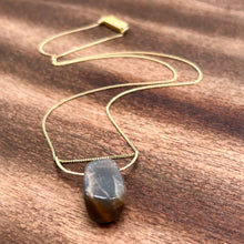 Load image into Gallery viewer, This stunning natural Black Moonstone gemstone has colors of slate grey and tan with a velvety silver flash across the surface when it is moved about in the light. This Black Moonstone is set on a hammered 14K gold-fill half-circle, hung from a dainty 14K gold-fill curb chain, and finished with a vintage-inspired pearl box clasp. The perfect necklace for those looking for a minimal design, but still want a unique gemstone rarely seen in most jewelry collections.
