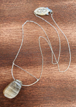 Cargar imagen en el visor de la galería, This stunning natural Black Moonstone gemstone has colors of slate grey and tan with a velvety silver flash across the surface when it is moved about in the light. This naturally-shaped Black Moonstone is set on a sterling silver half-circle, hung from a dainty sterling silver paper clip cable chain, and finished with a vintage-inspired pearl box clasp. The perfect necklace for those looking for a minimal design, but still want a unique gemstone rarely seen in most jewelry collections.
