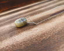 Load image into Gallery viewer, This stunning natural Black Moonstone gemstone has colors of slate grey and tan with a velvety silver flash across the surface when it is moved about in the light. This naturally-shaped Black Moonstone is set on a sterling silver half-circle, hung from a dainty sterling silver paper clip cable chain, and finished with a vintage-inspired pearl box clasp. The perfect necklace for those looking for a minimal design, but still want a unique gemstone rarely seen in most jewelry collections.
