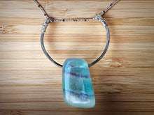 Load image into Gallery viewer, A colorful polished Fluorite stone is set on a hammered sterling silver semicircle with wire detail and strung on a sterling silver satellite curb chain, then finished with a vintage-inspired pearl box clasp. The sizable Fluorite stone has stunning colors of green and purple, and coupled with the satellite chain, it brings just enough sparkle to any ensemble. 
