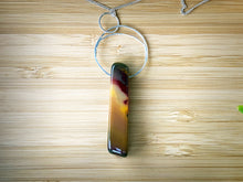 Load image into Gallery viewer, This natural Mookaite gemstone has been polished into a long rectangular shape and hung from a hammered sterling silver circle/half moon pendant and strung on a sterling silver curb chain. This stone is uniquely attractive with plenty of color including pink, green, yellow, mauve, red, and gray.
