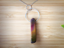 Cargar imagen en el visor de la galería, This natural Mookaite gemstone has been polished into a long rectangular shape and hung from a hammered sterling silver circle/half moon pendant and strung on a sterling silver curb chain. This stone is uniquely attractive with plenty of color including pink, green, yellow, mauve, red, and gray.
