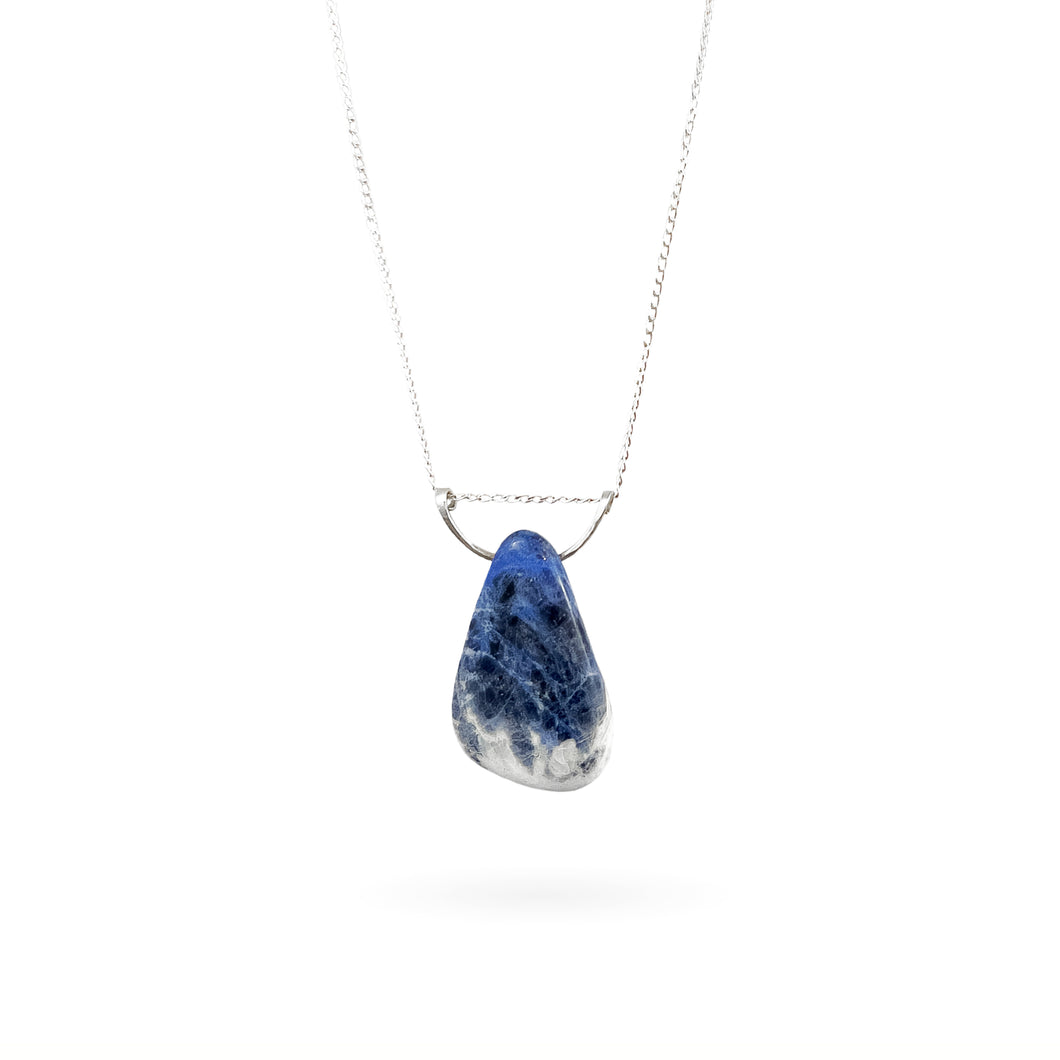 This large royal blue Sodalite gemstone pendant makes a statement with its “weathered blue jean” look. The oblong stone is suspended by a hammered sterling silver half-moon pendant and strung along a long sterling silver curb chain, and finished with a vintage-inspired pearl box clasp. A